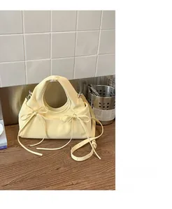 Dettaglio borsa a mano giallo tenue con fiocchi e tracolla regolabile in pelle
