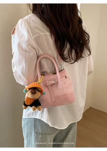 Pink textured bucket bag with a cute dog plush charm and adjustable shoulder strap detail