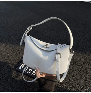 Detail of white leather bucket bag with silver twist lock on dark asphalt background