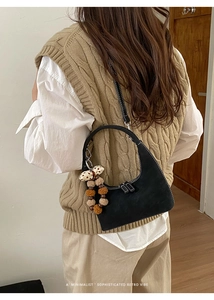 Detail einer schwarzen Hobo-Tasche mit Kontrastnähten und Plüsch-Anhänger für Damen