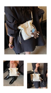 Detail view of a white quilted bucket bag with gold chain strap and teddy bear charm