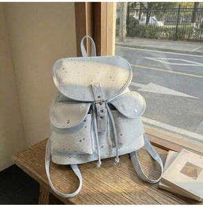 Detail of light blue star print canvas backpack featuring silver stars and front flap pockets