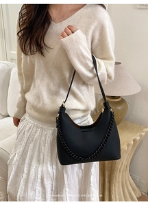 Close-up of a black minimalist retro shoulder bag with a textured chain detail