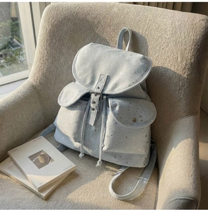 Detail view of light blue star print backpack on sofa with natural sunlight effects