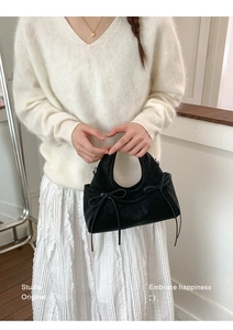 Dettaglio di una borsa nera in pelle scamosciata con lacci decorativi a fiocco in studio