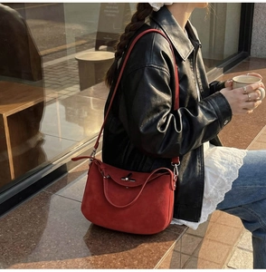 Street style shot of a red suede bucket bag with dual handles and elegant texture
