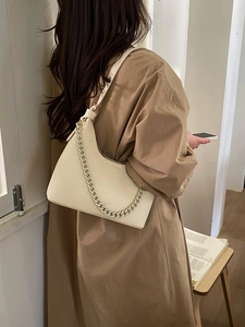 Detail view of cream leather shoulder bag with thick chain handle and lychee texture