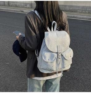 Outdoor shot showing the silver star patterns on the light gray canvas backpack for students