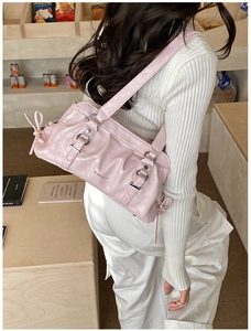 Detailed shot of pink pleated shoulder bag with metal rings and bow tie accents