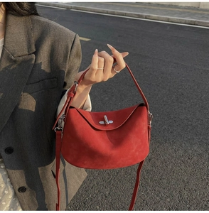 Detail of red suede shoulder bag with silver turn-lock and adjustable crossbody strap