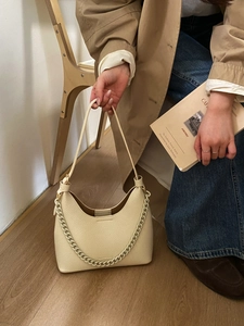 Detail of a creamy beige lychee grain leather handbag with stylish chain and shoulder strap