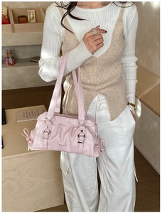 Detail of pink ruched underarm bag with silver buckle and bow knot on a model