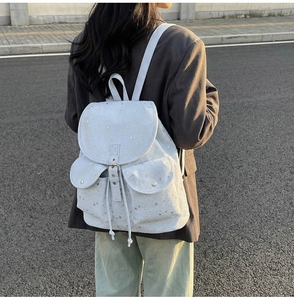 Star pattern canvas backpack with drawstring closure and buckle on a model in street style