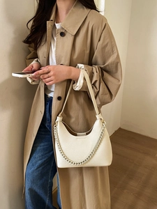Close-up of beige lychee textured leather crescent bag with matte chain strap