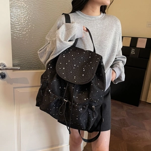 Close-up of black drawstring backpack with silver star patterns and flap pocket detail