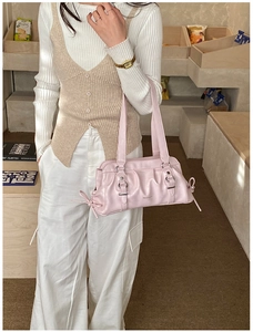 Detail of pink pleated underarm bag with silver buckles on a stylish knitted sweater