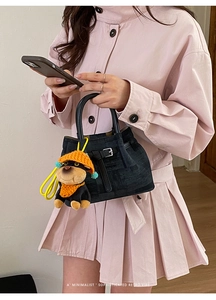 Chic black textured handbag with leather buckle and colorful dog charm accessory