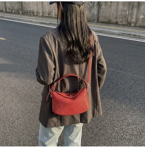 Detail of red semicircular crossbody bucket bag with twist lock and adjustable strap