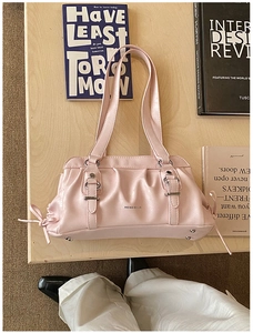 Detail of pink pleated faux leather shoulder bag with silver buckles and bow decoration