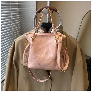Detail of pink quilted bucket bag with golden chain strap and drawstring closure