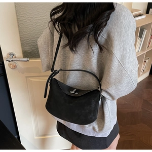 Detail of a black matte crossbody bucket bag with metal twist lock shown on a model
