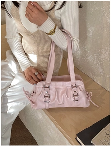 Detail of light pink pleated shoulder bag featuring metal rings and drawstring accents