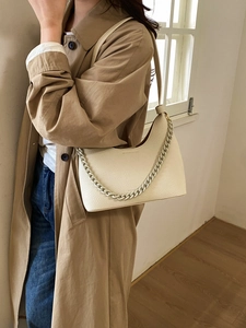 Close-up of off-white lychee leather crescent bag with matching chain and logo detail