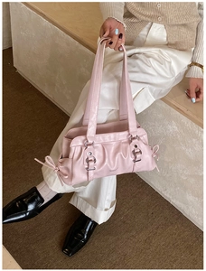 Detail of pink pleated underarm bag with decorative metal ring and bow accents