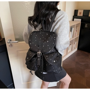 Close-up of black star pattern canvas backpack with flap closure and silver metal buckles