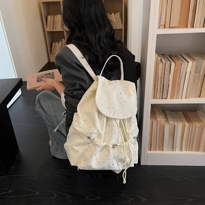Detail of cream backpack with silver stars showing side zipper and drawstring closure