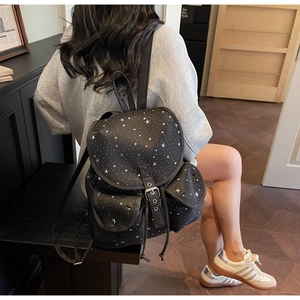 Star pattern black canvas backpack shown on model in a stylish indoor setting