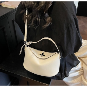 Rear view of a model wearing a white minimalist bucket bag with a metal twist lock