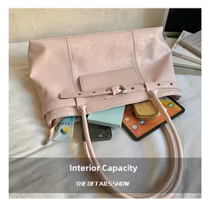 Detail view of large pink leather tote bag showing internal capacity with laptop and cosmetics