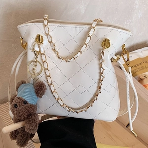 Chic cream quilted bucket bag with golden chain strap and a cute teddy bear charm