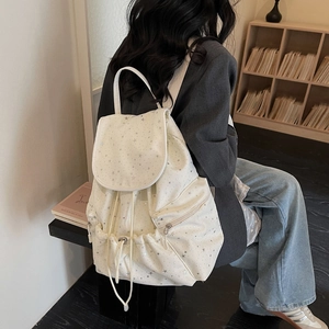 Detail showing the white drawstring backpack with silver star patterns on a lifestyle background