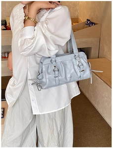 Detail of light blue pleated underarm bag with silver metallic buckle and shoulder strap
