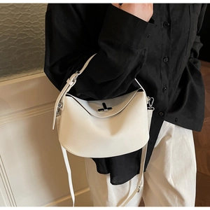 Detail of white leather bucket bag with silver rotating lock and adjustable shoulder strap
