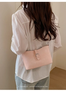 Detailed view of light pink retro shoulder bag with silver buckle and leather texture
