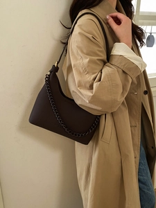 Detail of dark brown pebble leather hobo bag with thick chain strap and crossbody design