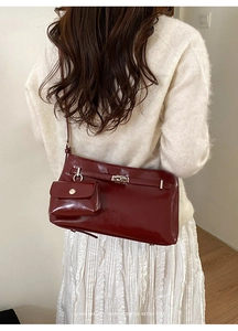 Burgunderfarbene Retro-Eimertasche mit Mini-Beutel an weißem Strickoutfit im Detail