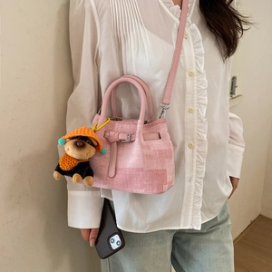 Pink woven bucket bag with cute plush dog charm shown on a crossbody model outfit