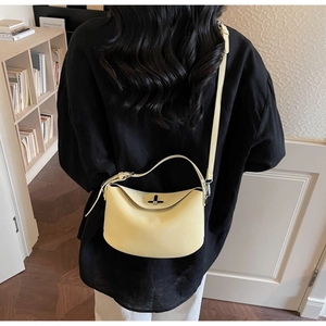 Detail of a creamy yellow leather bucket bag featuring unique folded structure and metal clasp
