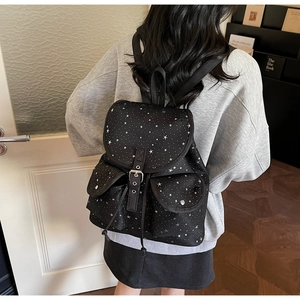 Detailed view of black canvas star pattern backpack with drawstring and metal buckles