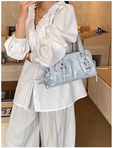 Detail of light blue PU shoulder bag with pleated texture and silver metal buckle
