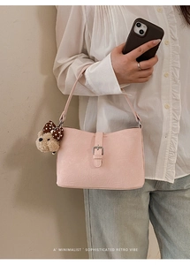 Detail of pink retro underarm bag with lychee texture and cute bear charm accent