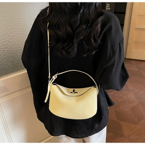 Detail shot of the cream leather crossbody bag featuring the metallic twist lock closure