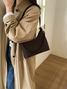 Close-up of deep brown leather shoulder bag featuring textured lychee grain and chain detail