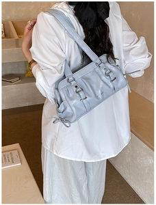 Detail of light blue shoulder bag with silver hardware and bow tie ribbon decoration