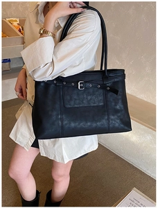 Detail of black tote bag with vintage strap, silver buckle, and textured finish