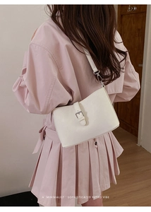 Minimalist beige underarm bag detail featuring a retro buckle and smooth leather texture